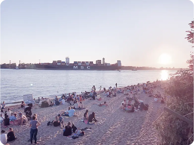Strand an der Elbe bei Sonnenuntergang mit goldenem Himmel und ruhigem Wasser