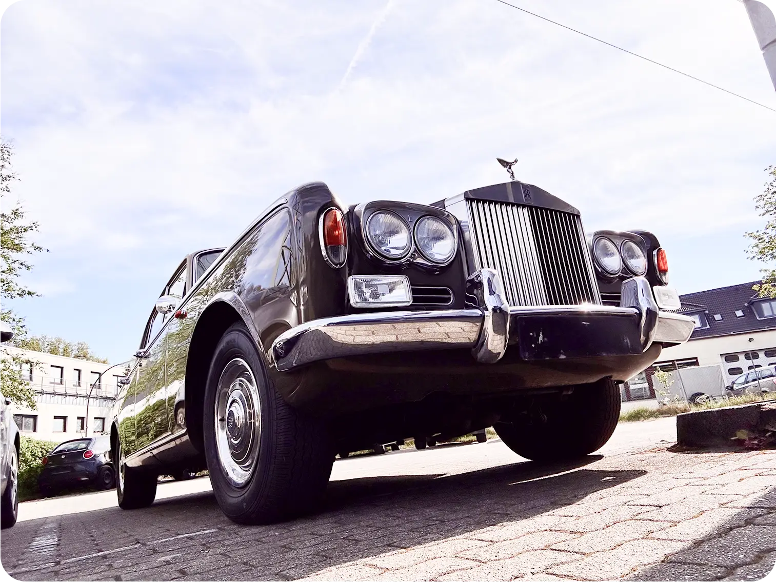 Luxusauto Rolls-Royce in Schwarz, aus der Froschperspektive von vorne fotografiert bei sonnigem Wetter