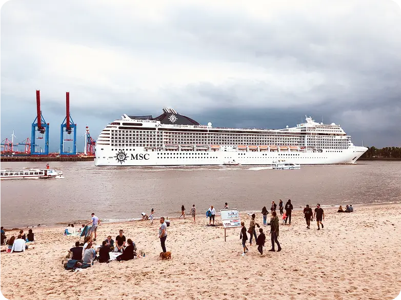 Strand an der Elbe in Hamburg mit großem Kreuzfahrtschiff auf dem Fluss